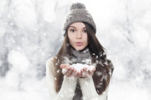 Winter portrait. Young, beautiful woman blowing snow